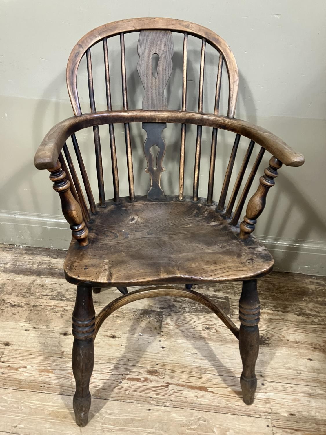 A 19th century elm and ash low back Windsor armchair, turned legs joined by a crinoline stretcher