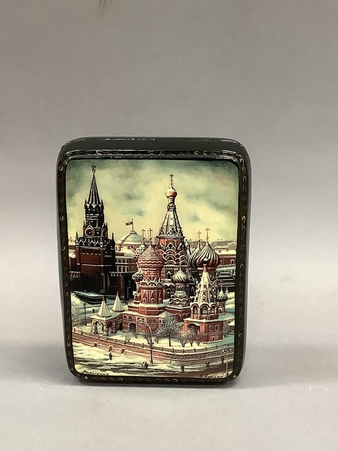 A modern Russian lacquered hinged box, the lid hand painted with a winters scene of St Basil's