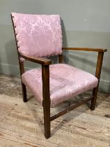 An early 20th century oak open armchair upholstered in pink damask