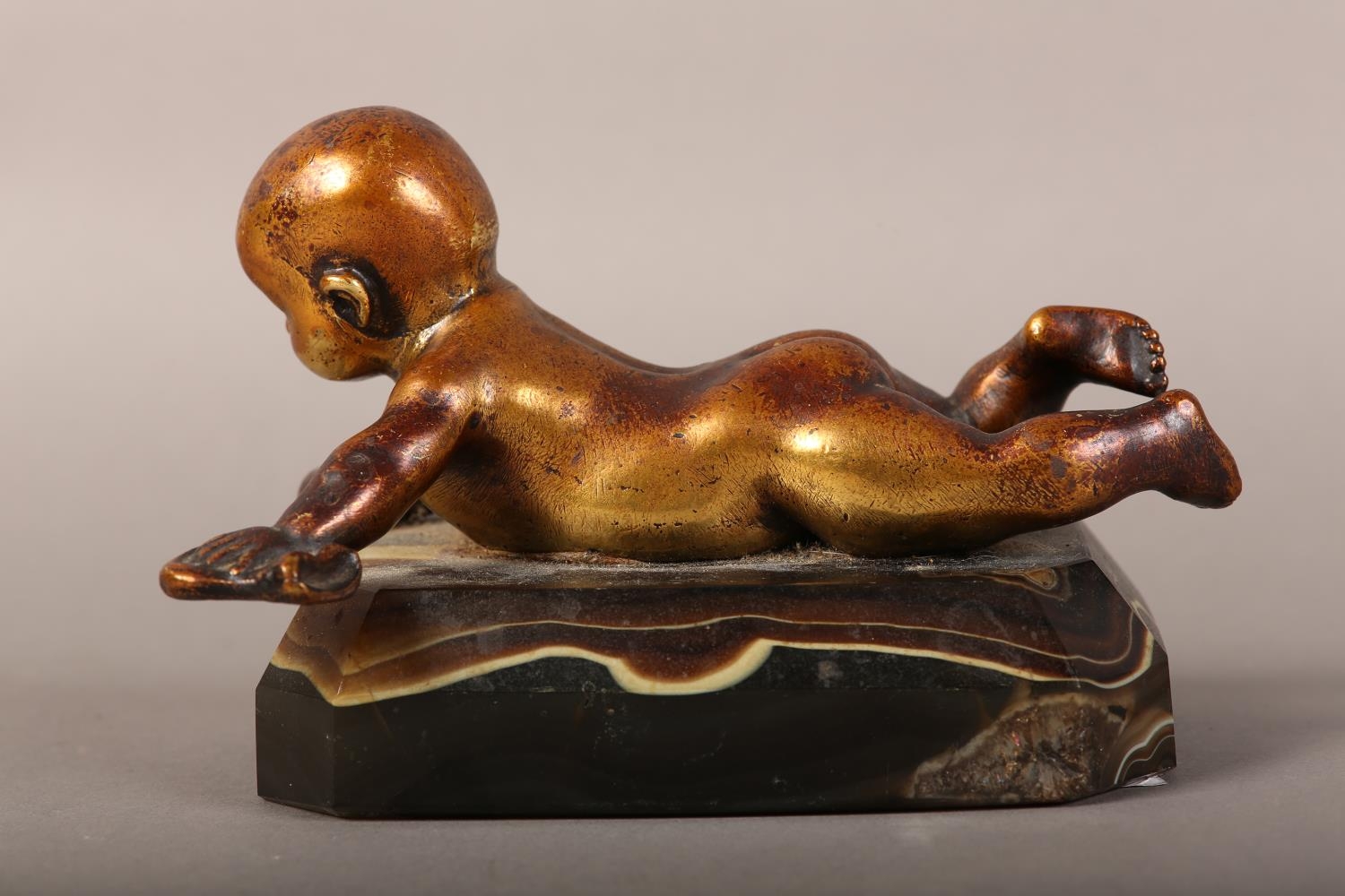 A gilded bronze figure of an infant lying on it's stomach, on an agate base, 14.5cm long x 9.5cm - Image 4 of 4