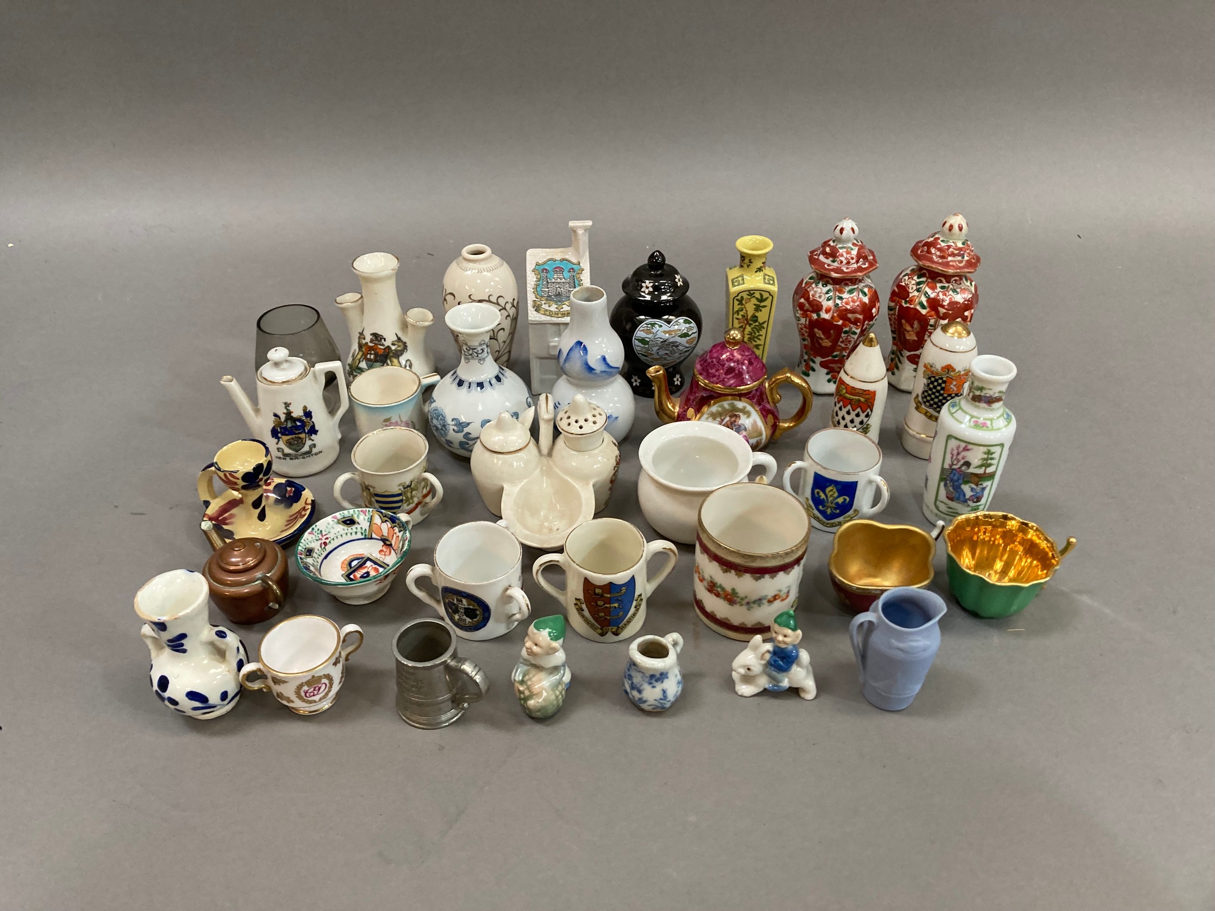 A collection of miniature china and pottery including vases, crested chinaware, cups, figures, etc