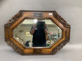 A 1920s oak framed wall mirror, the octagonal glass within a broad frame with beaded rim, overall