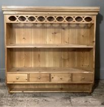 A pine hanging shelf with carved frieze, middle shelf above four small drawers and shelf below