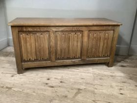 An oak ottoman with linen fold front and on stile feet