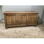 An oak ottoman with linen fold front and on stile feet