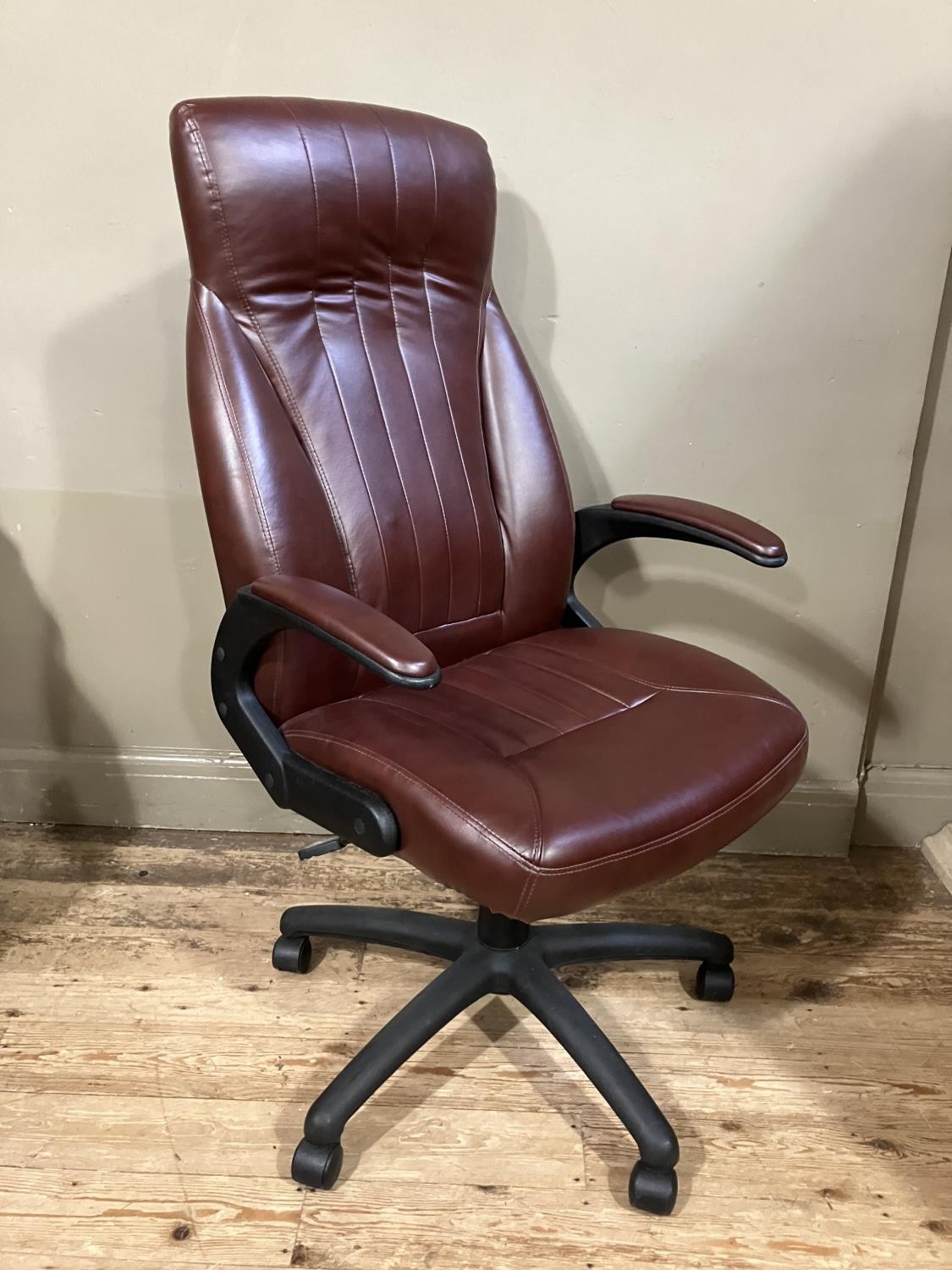 A swivel office chair in burgundy leather effect upholstery