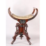 A Late 19th century mahogany revolving piano stool, the dished seat with open curved upright arms,