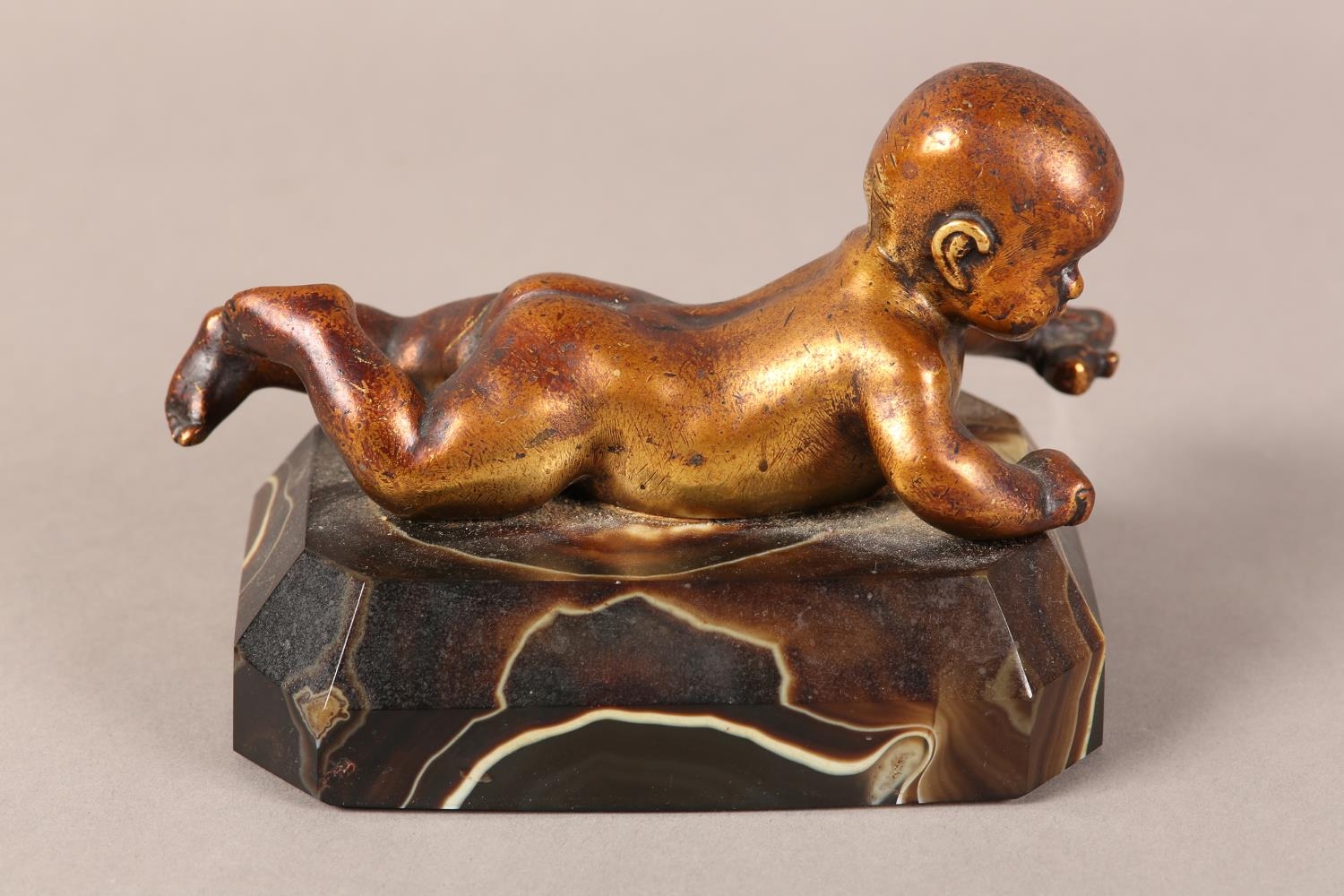 A gilded bronze figure of an infant lying on it's stomach, on an agate base, 14.5cm long x 9.5cm - Image 2 of 4