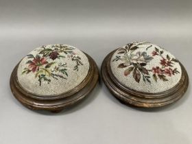 A pair of late Victorian circular footstools with needlework and beaded floral covers on bun feet