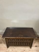 A small reproduction oak coffer having a planked top, the front carved with trefoils and arcading on