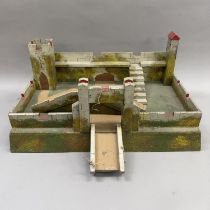 A wooden toy castle with drawbridge and turrets, relief painted in greens and browns