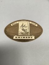 A. Bains Rugby card for Grimsby, shaped and printed as a rugby ball. 6cm x 9.5cm.
