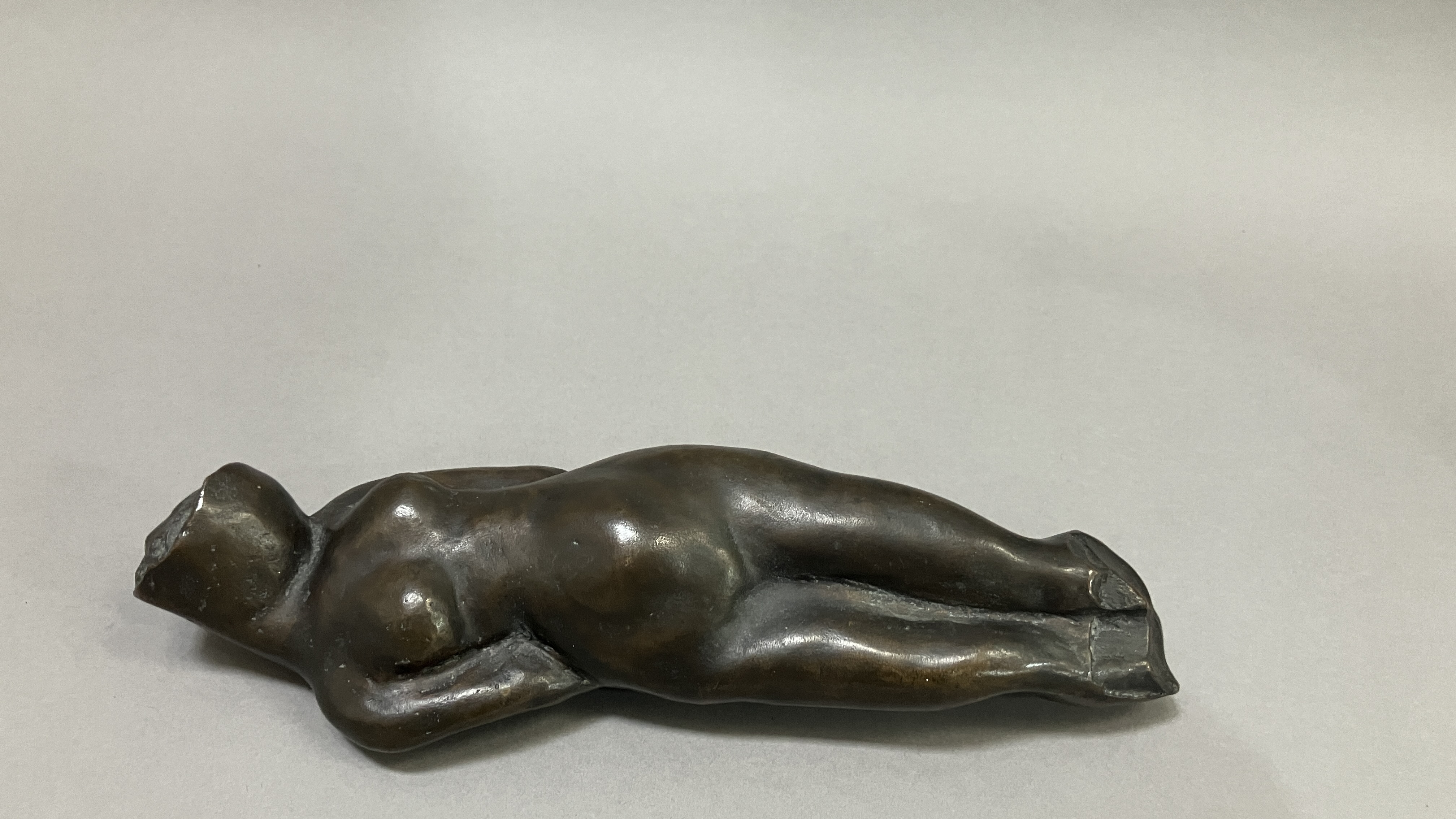 British School mid 20th century, A bronze female nude figure, reclining, 22cm long
