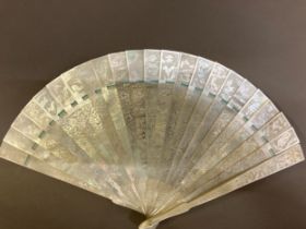 A Chinese Mother of pearl brisé fan, with 21 inner sticks and two guards, entirely etched with