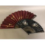 A black wood fan, carved and gilded, early 20th c, mounted with a silk leaf, painted with a courting