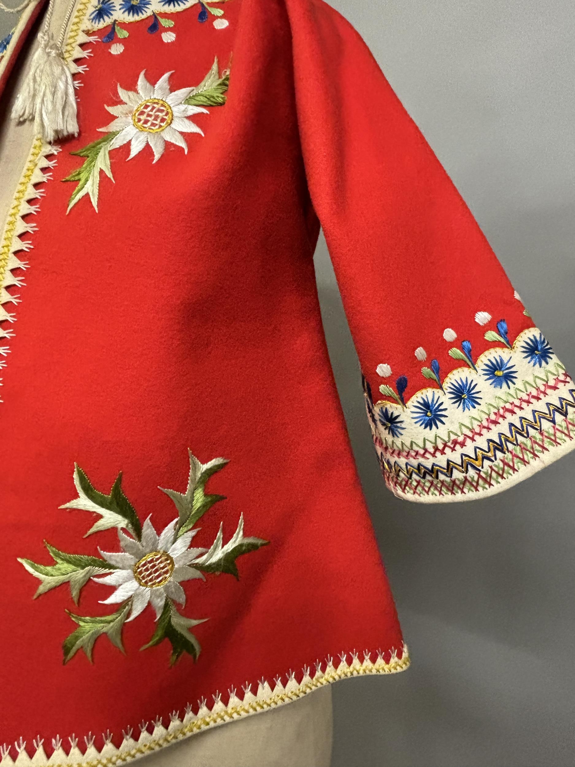 A Child’s folk dress coat, in red wool with cream cuffs, seam and collar, heavily embroidered with - Image 3 of 7