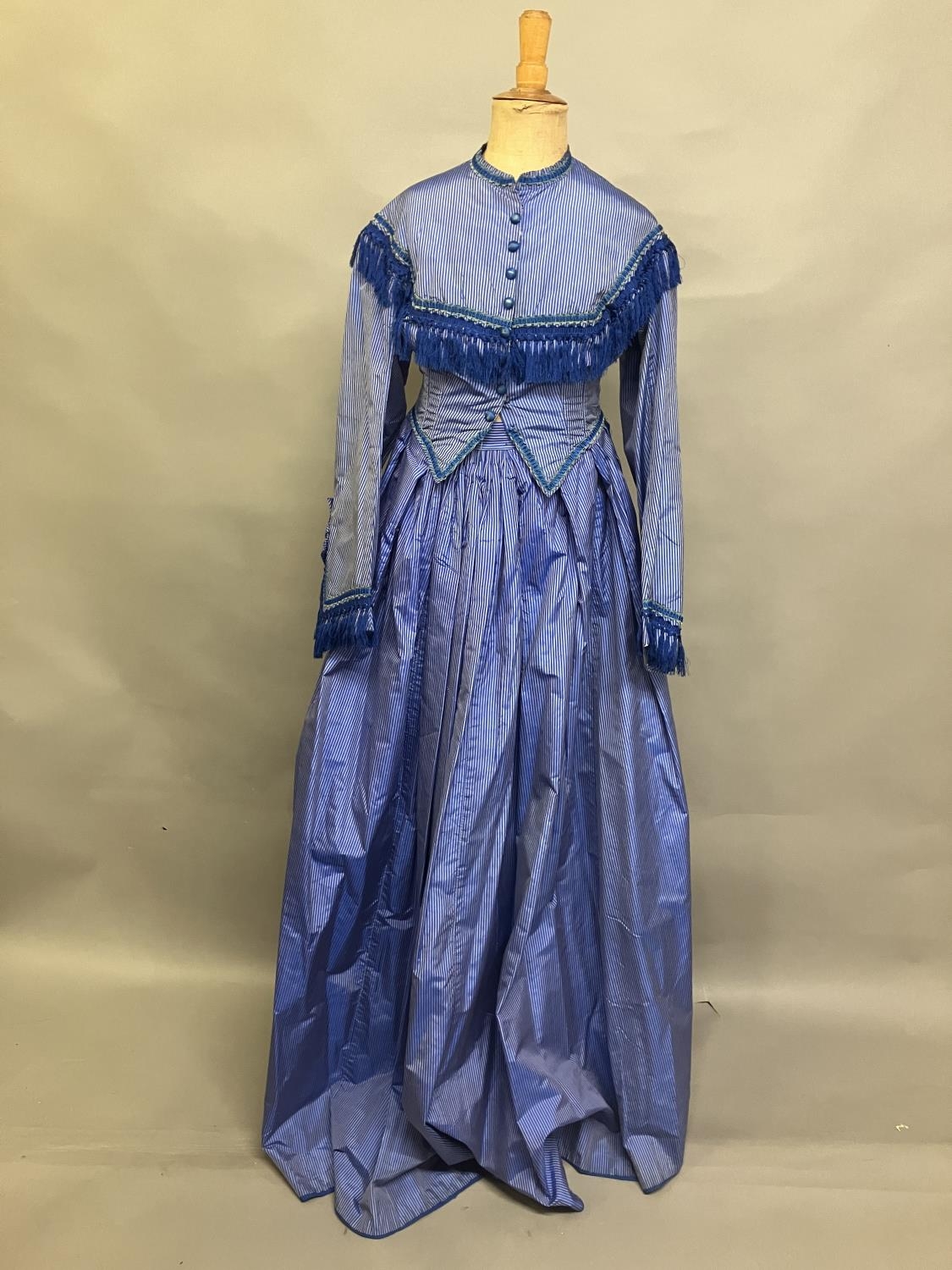 C 1865, a striped blue silk two-piece ensemble, short bodice with rear detail, trimmed with