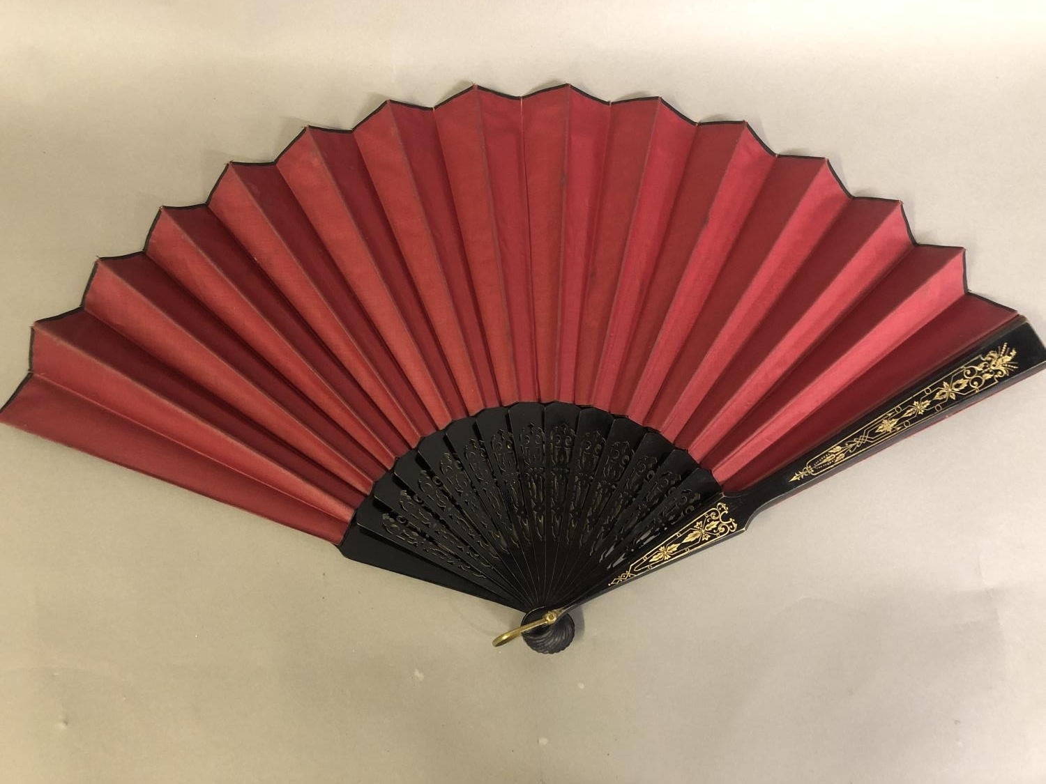 A black wood fan, carved and gilded, early 20th c, mounted with a silk leaf, painted with a courting - Image 2 of 4