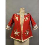 A Child’s folk dress coat, in red wool with cream cuffs, seam and collar, heavily embroidered with