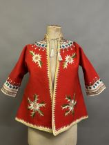 A Child’s folk dress coat, in red wool with cream cuffs, seam and collar, heavily embroidered with