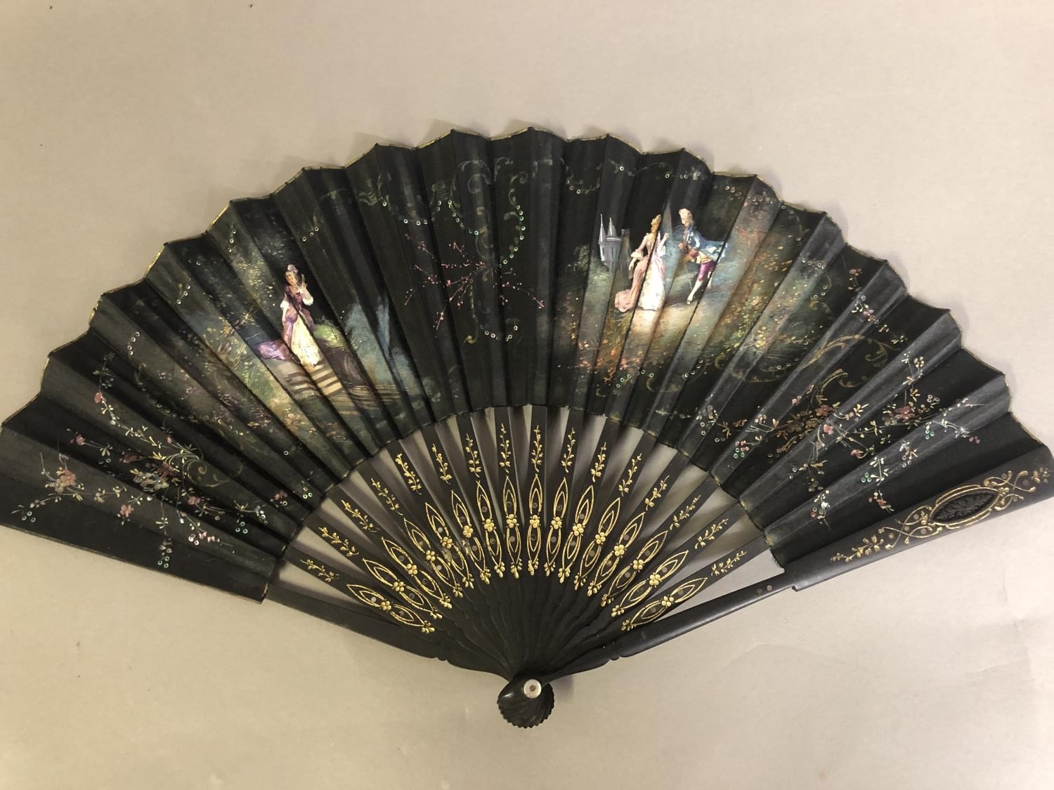 A black wood fan, carved and gilded, early 20th c, mounted with a silk leaf, painted with a courting - Image 3 of 4