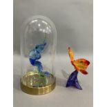 A Swarovski crystal blue frog on branch in glass dome together with an orange butterfly on purple