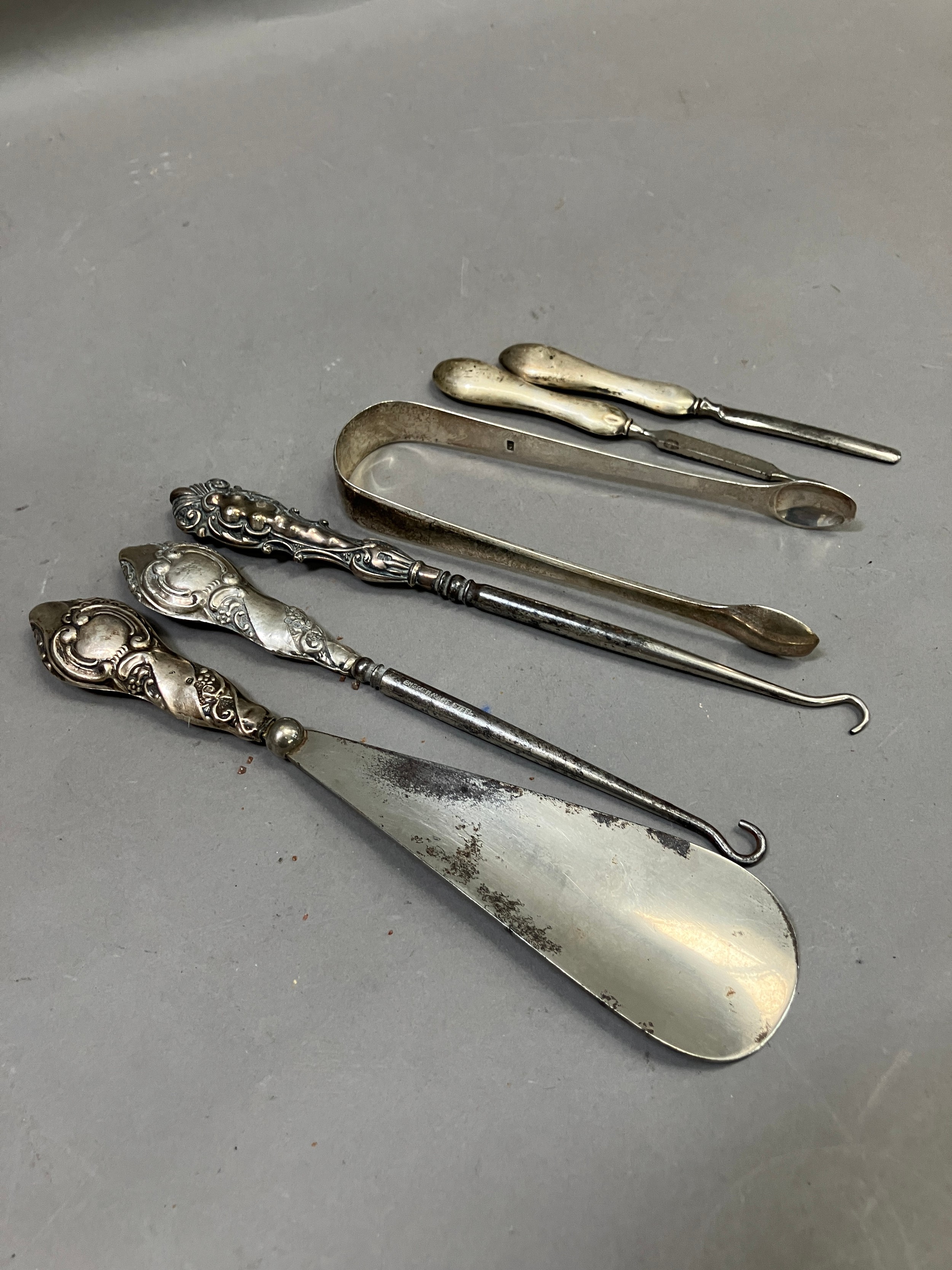 Five silver handled dressing and manicure items including button hooks, shoe horn, file and