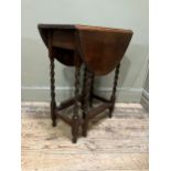 A 1920/30s oak oval gate leg table having twin drop leaves and on slender barley twist supports
