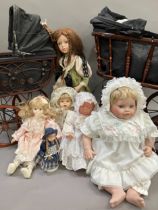 A collection of six modern porcelain dolls in costume, together with two Victorian style prams