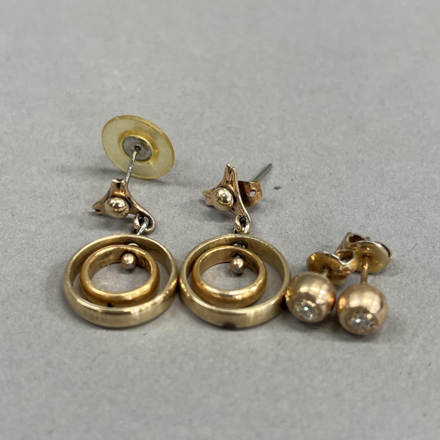 A pair of ear pendants each of concentric yellow metal rings (tests as gold) hung on base metal post