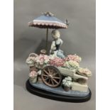 A Lladro figure group, Flowers of the Season, of a girl with flower cart under an umbrella, 30cm