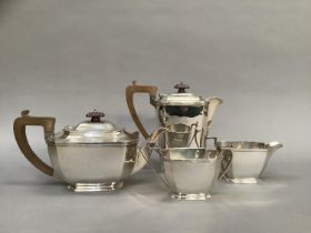 A four piece silver tea service comprising, tea pot and hot water jug with composite handles, two