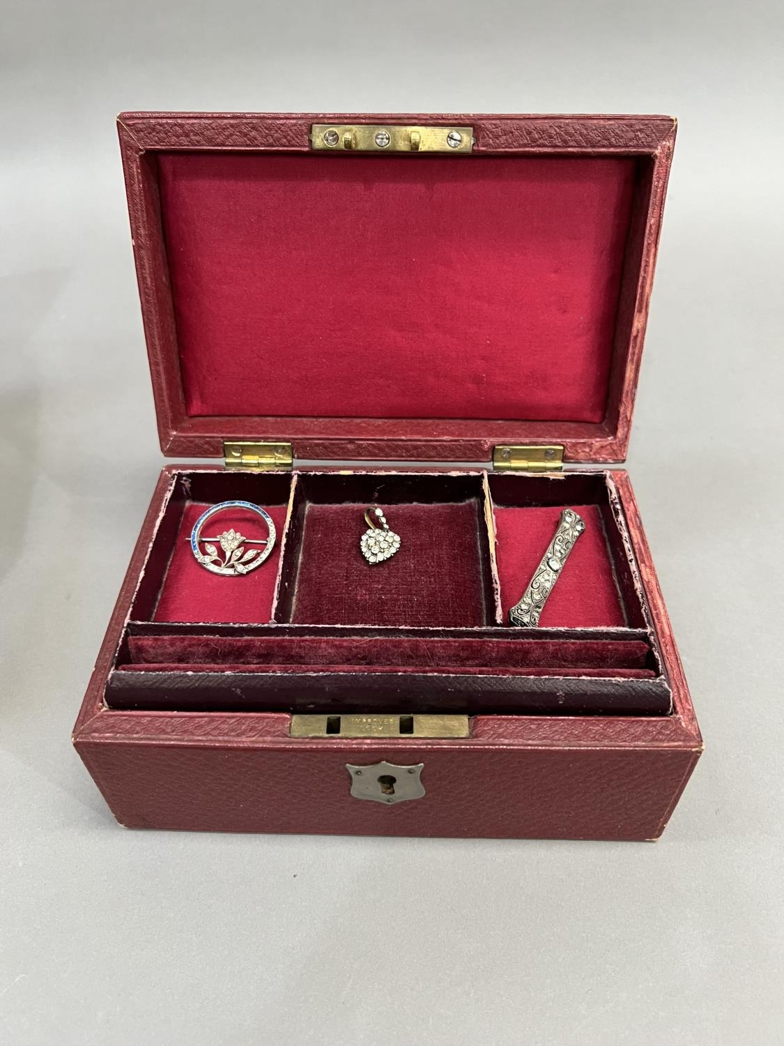 AN early 20th century jewellery case covered in faux red leather with tiered red velvet lining