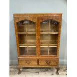 A figured walnut bookcase having two arch profile doors glazed, the interior fitted with adjustable