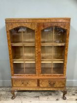 A figured walnut bookcase having two arch profile doors glazed, the interior fitted with adjustable