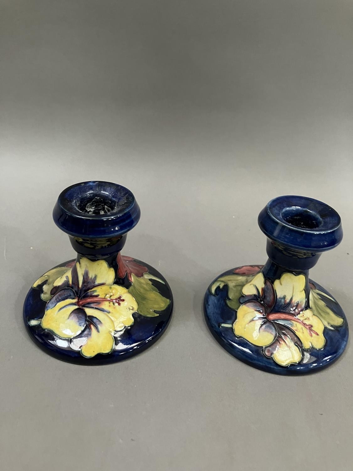 A pair of Moorcroft hibiscus pattern candlesticks, 19cm high