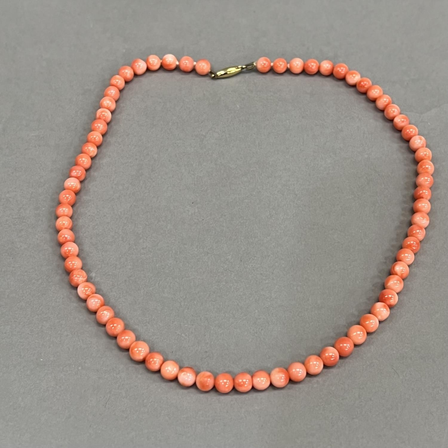 A necklace of spherical coral beads, each approximate 6mm diameter fastened with 9ct gold snap,