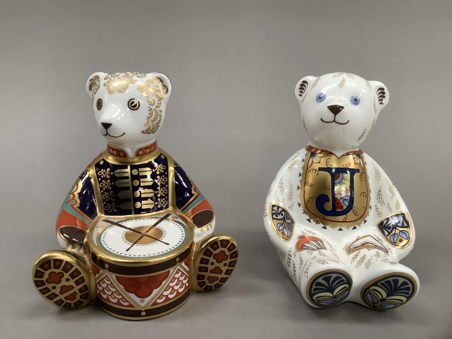 A Royal Crown Derby alphabet bear, gold button, together with drummer bear, 10.5cm and 10cm high