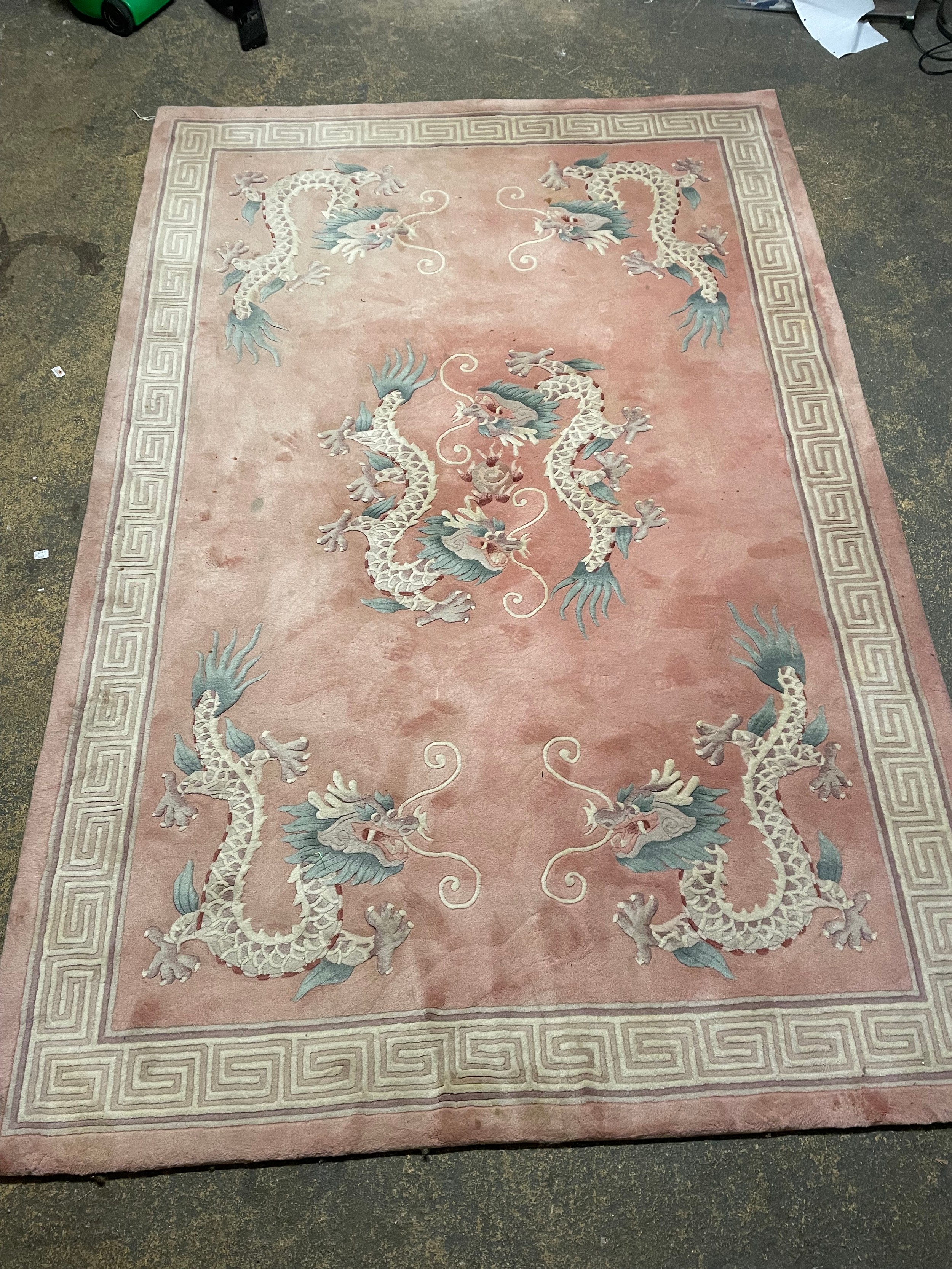 A Chinese pink rug bearing motifs of dragons in a geometric border