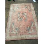 A Chinese pink rug bearing motifs of dragons in a geometric border