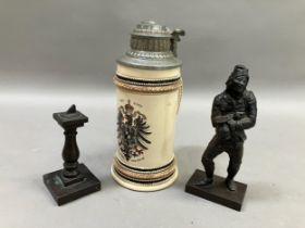 A metal figure of a taverner holding a jug of ale, on plinth base inscribed beneath in German, 17.5