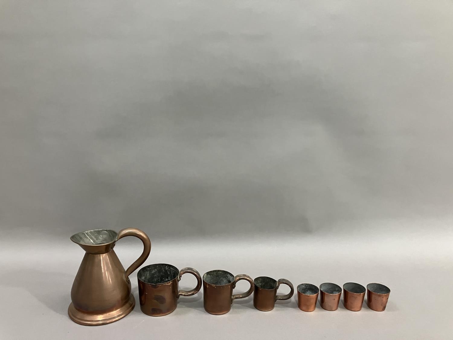 A copper pint measure, a set of three measures in the form of mugs, half pint being the biggest