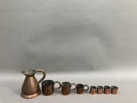 A copper pint measure, a set of three measures in the form of mugs, half pint being the biggest