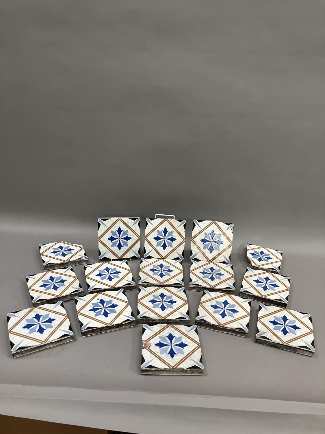 A set of thirteen 19th century Minton tiles glazed in white with a two-shade blue stylised flower to