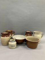 Three stoneware jugs with brown half glaze together with stoneware bowls another jug and a jar