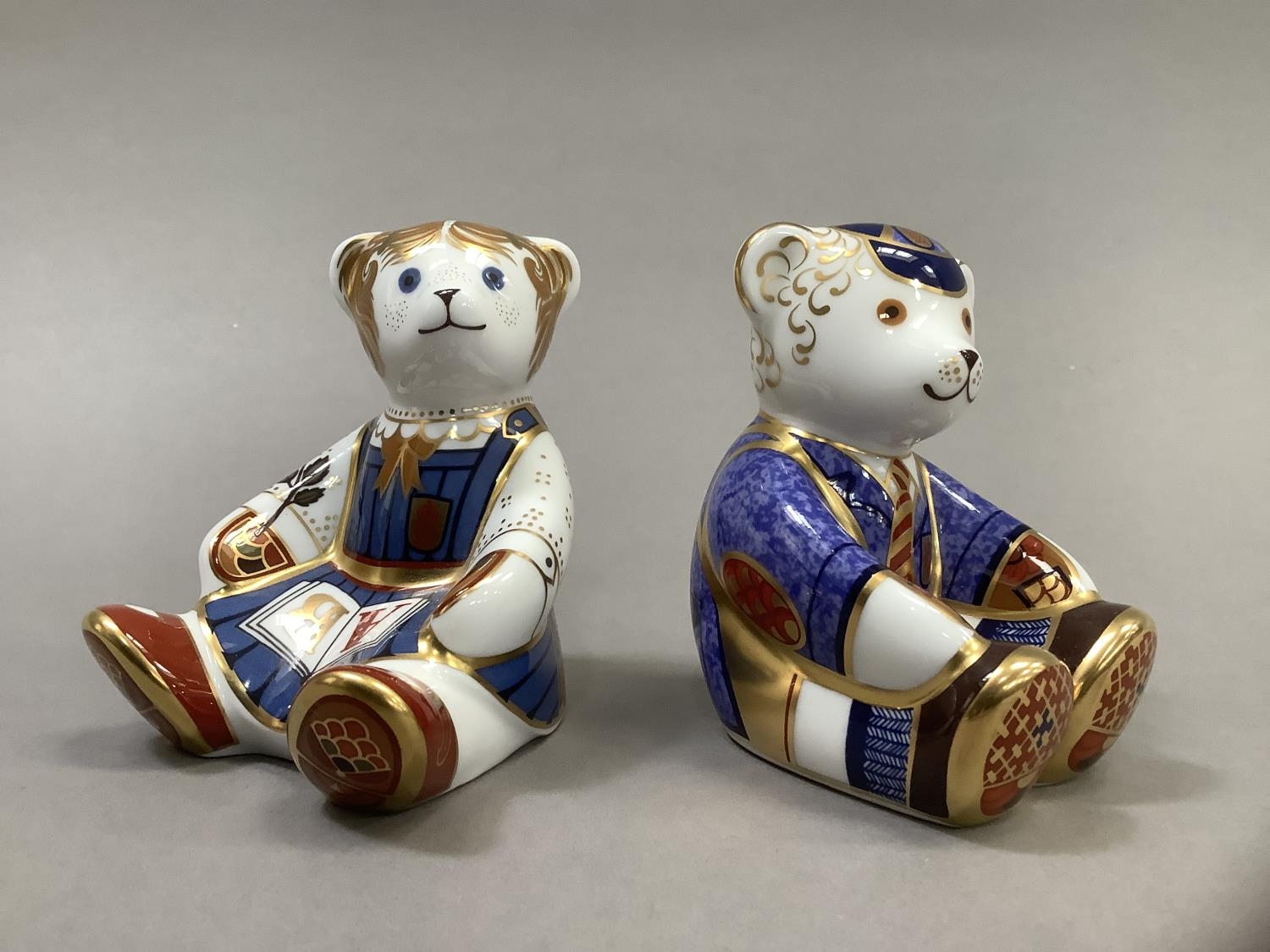 A Royal Crown Derby school girl teddy and school boy teddy, gold buttons, 8.5cm high