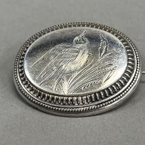 A Victorian oval silver brooch, engraved with a song bird perched in grasses raised against a