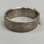 A stiff hinged bangle in silver, circa 1958, half foliate scroll engraved, approximate width 22mm,