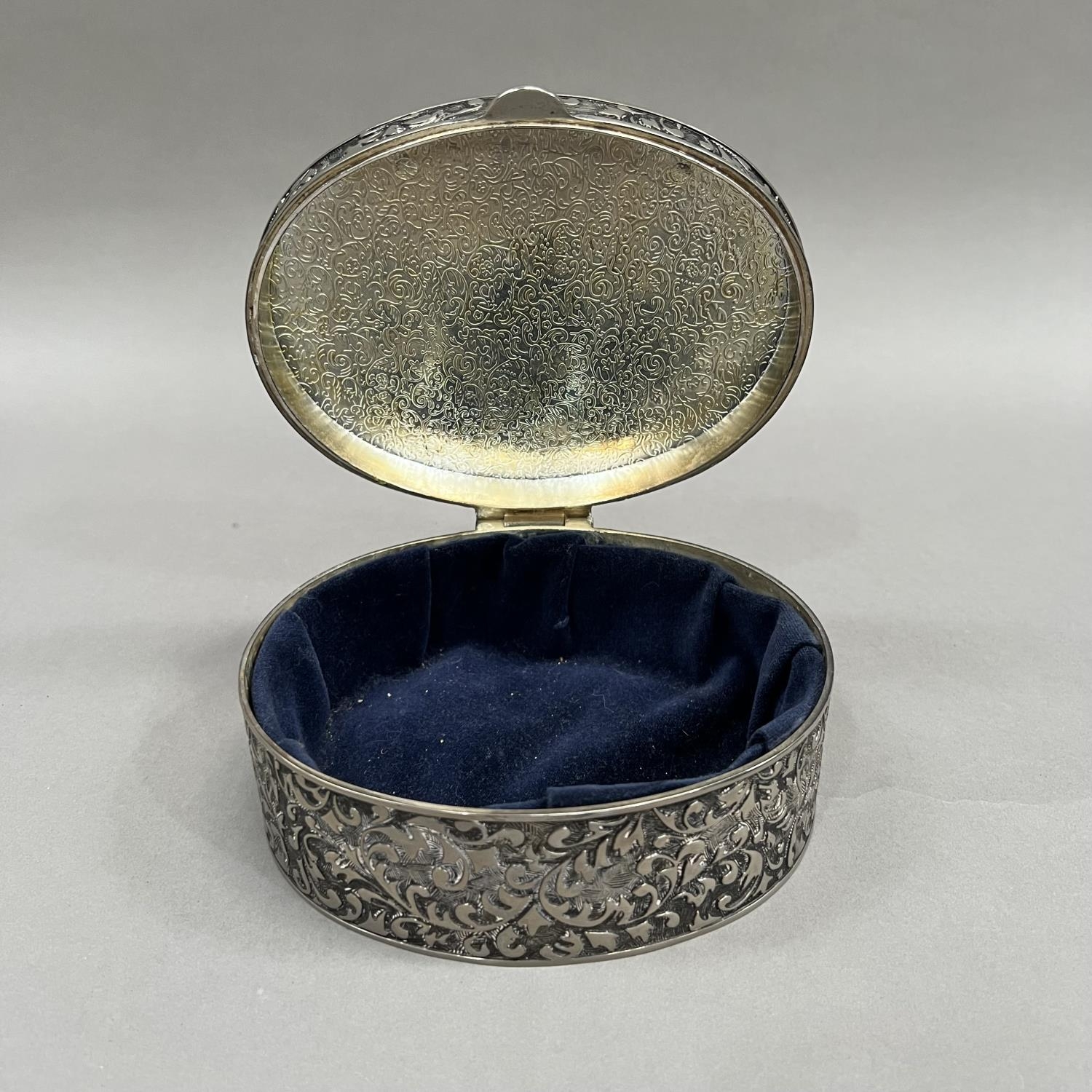 An oval box in white base metal with hinged lid, all over foliate chasing and an open circular - Image 3 of 3