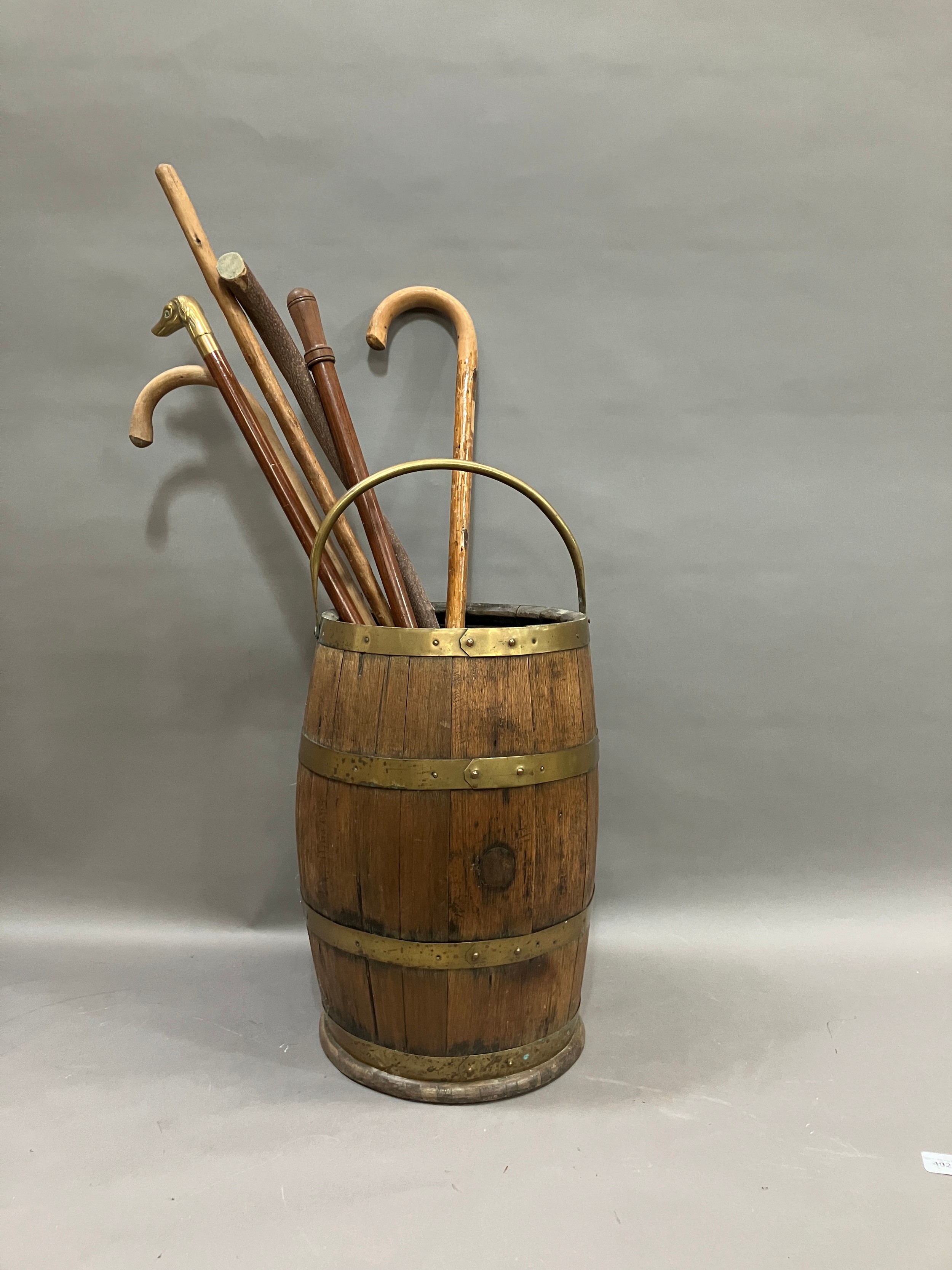 A brass bound and oak coopered barrel stick stand with swing handle together with several walking